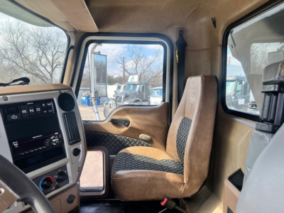 Cab interior of a 2018 Mack GU713 dump truck showing front seats, dashboard with gear selector, and side window view.