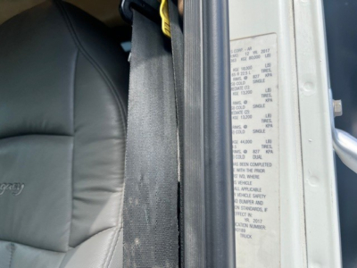Vehicle door jamb label on a 2018 Mack GU713 dump truck showing VIN and build data text in a close-up window