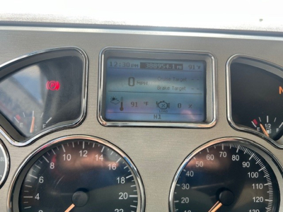 Dashboard of a Mack GU713 truck showing digital display with 0 MPH, 91°F, 12:30 PM, Brake Target, and various gauges; left and right gauges and warning lights visible.