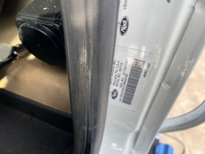 Vehicle door jamb area showing VIN sticker and barcodes on a 2018 Mack GU713 dump truck. Visible labels include a GE/LG type barcode and vehicle info sticker.