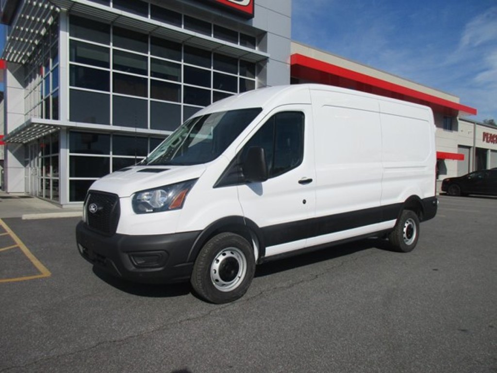 Ford Transit cargo van in a dealership lot, white exterior, black bumper, side view with short wheelbase.
