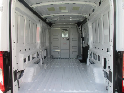 Ford Transit cargo van interior with empty cargo space and rear doors open, showing metal walls and floor.