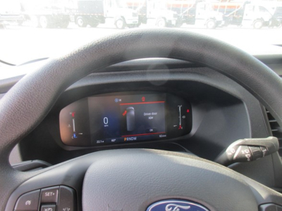 Ford Transit cockpit view showing digital instrument cluster with speed, gear indicator PRNDM and steering wheel in foreground.