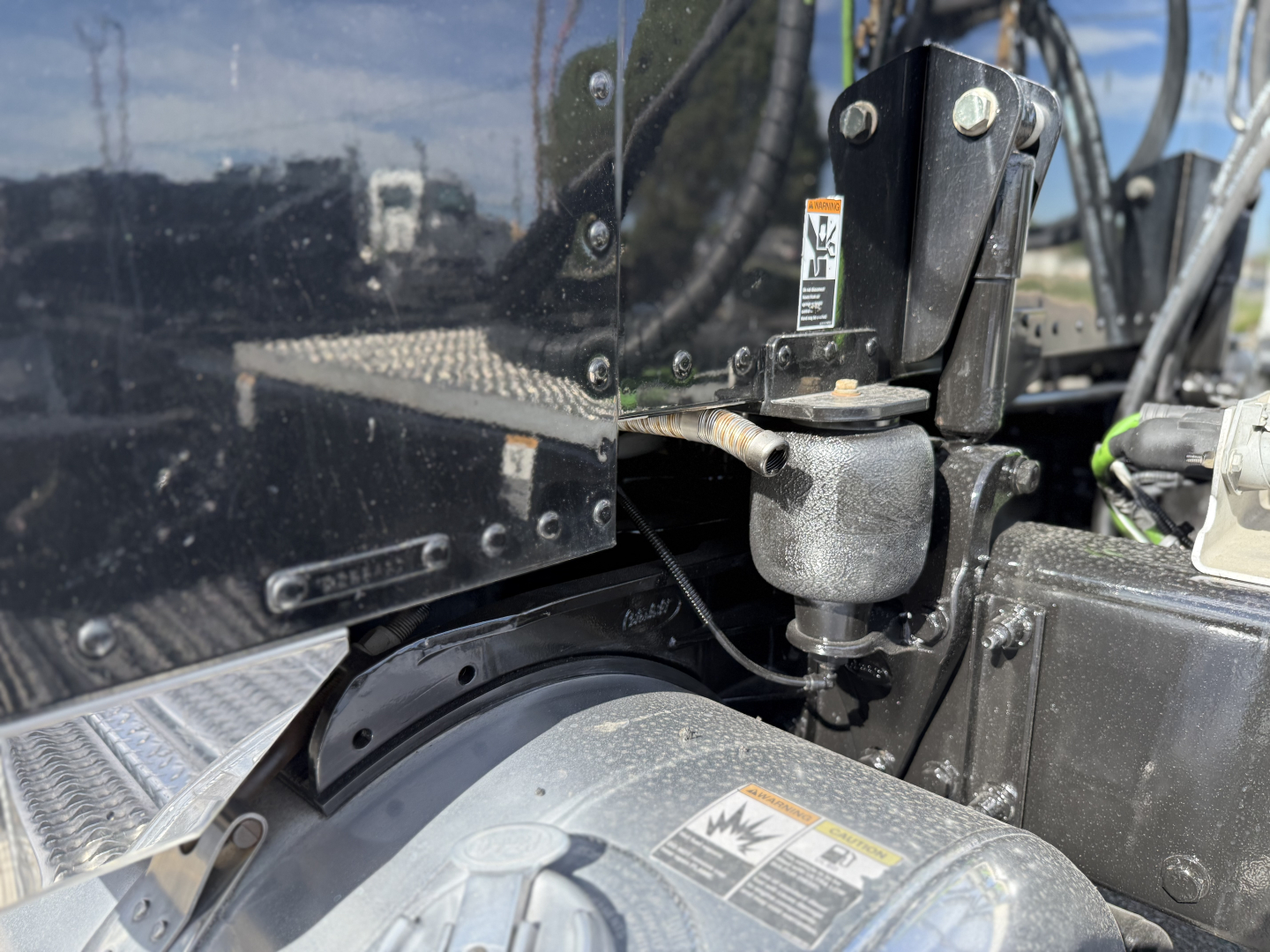 Conventional sleeper tractor step and hood area of 2019 Peterbilt 389 showing hydraulic component and attachment bracket with label text visible