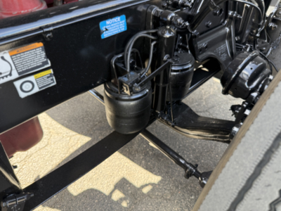 Peterbilt 389 undercarriage showing front suspension components and air tanks with hoses and wiring.
