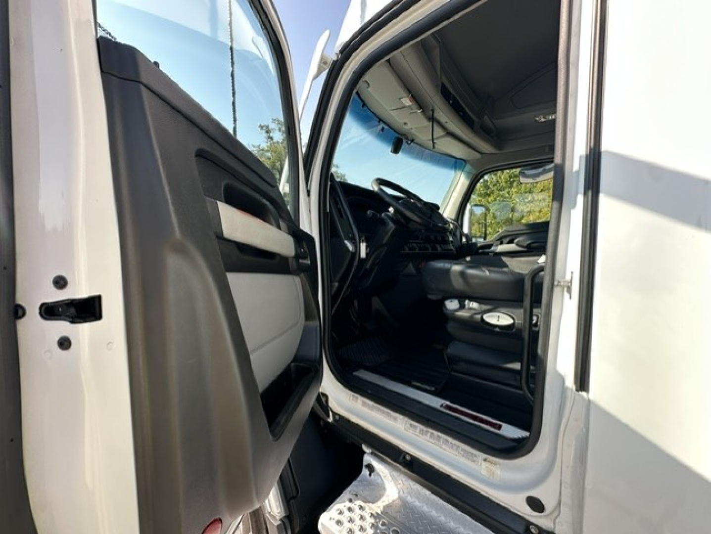 Kenworth T680 truck cab interior view from open driver door showing steering wheel and dashboard