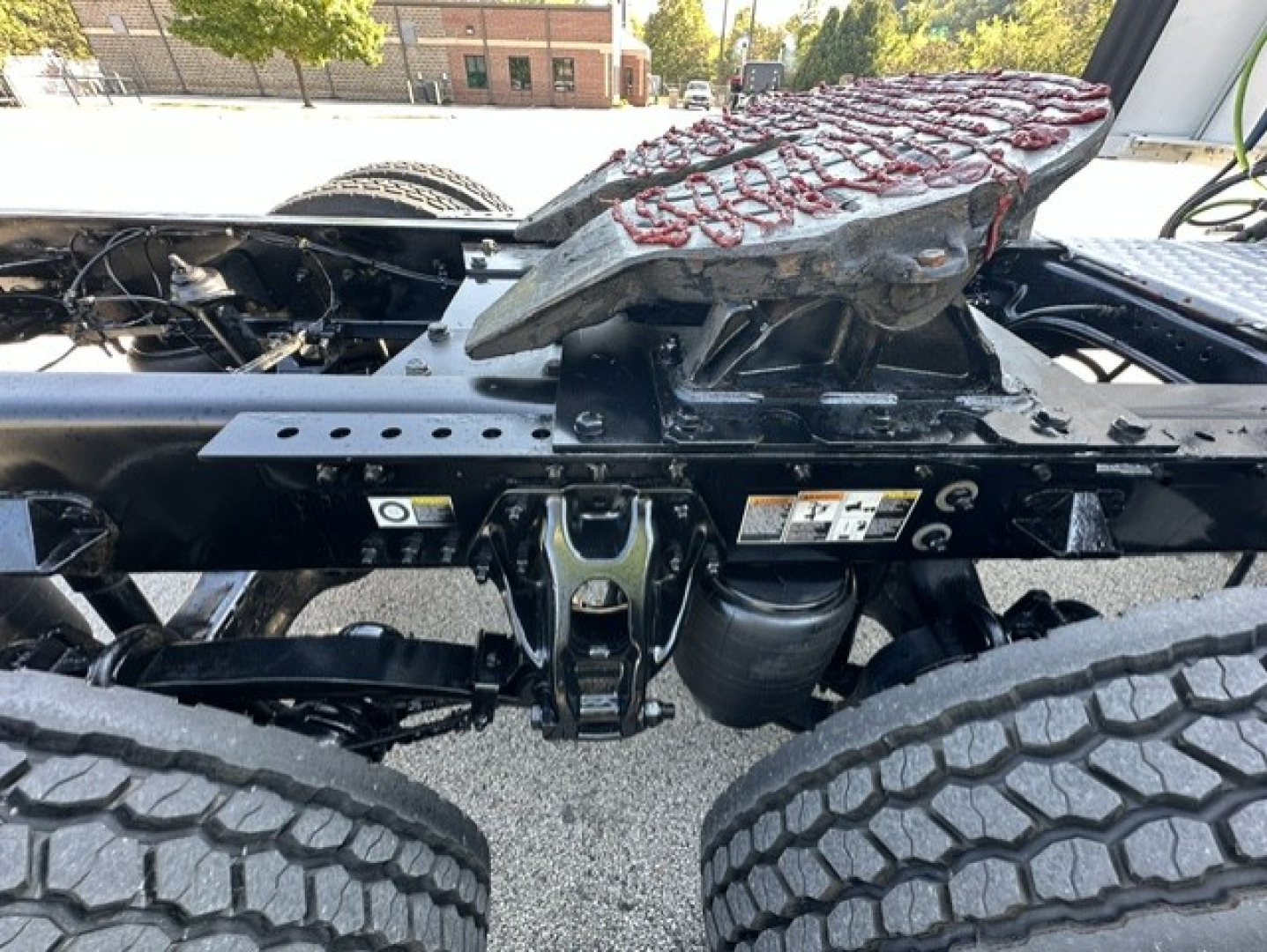 Kenworth T680 chassis undercarriage showing dual rear wheels, hitch assembly, and frame with identification labels.