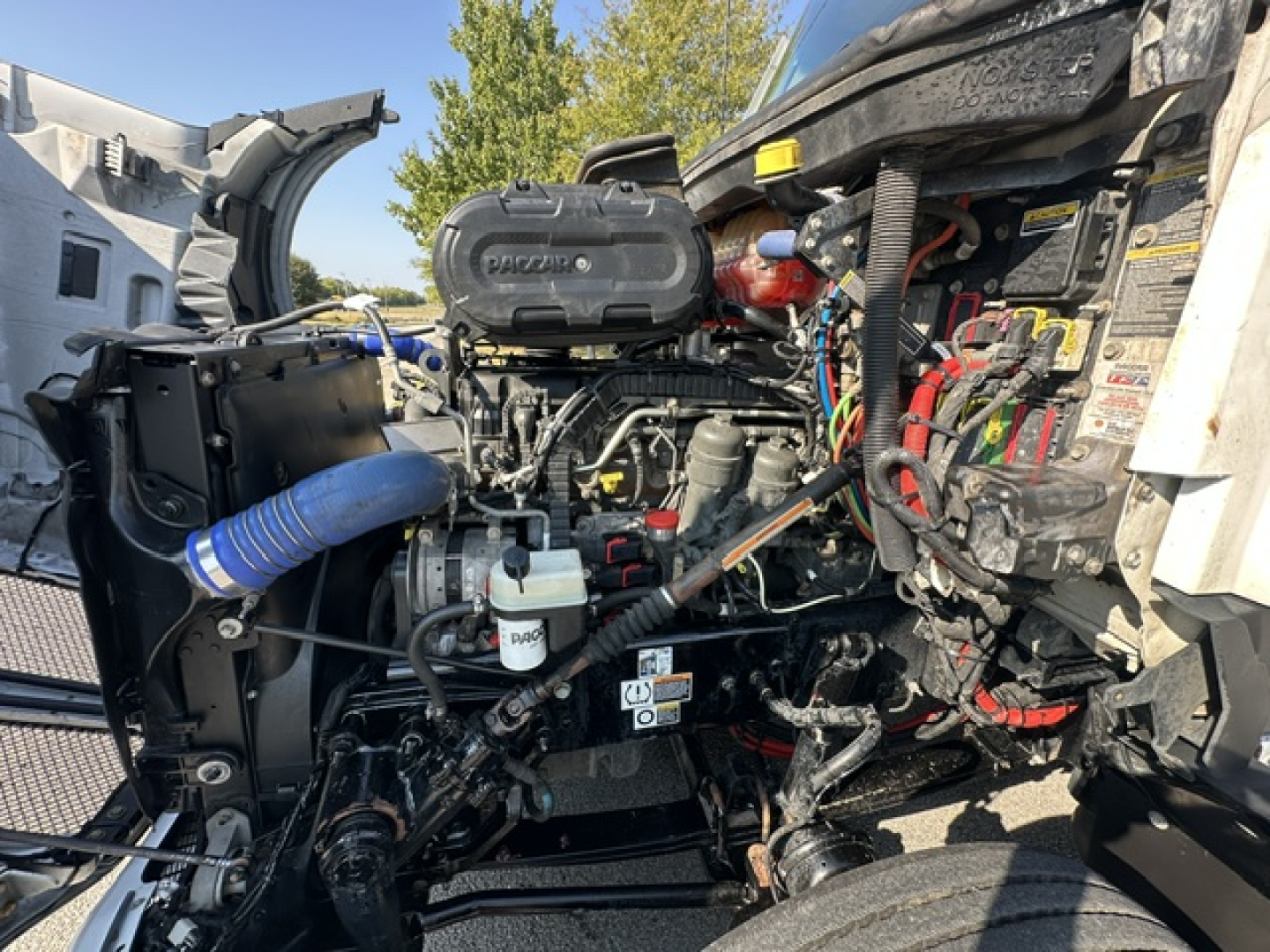 Kenworth T680 engine bay with clean diesel engine and various hoses; visible labels on the radiator support and engine components.