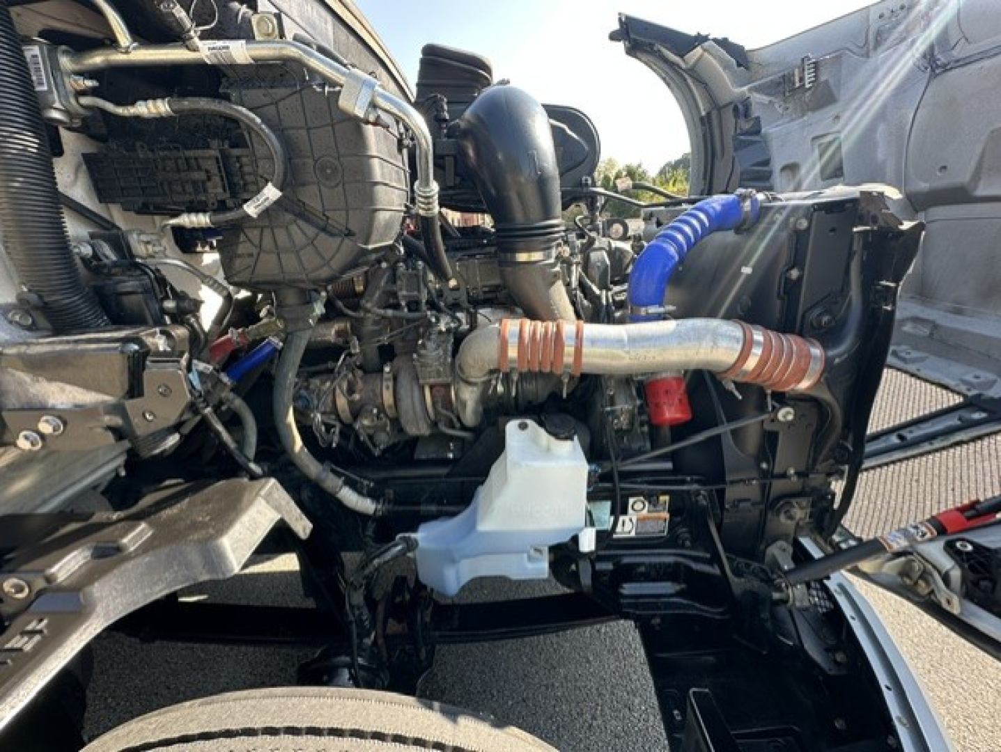Kenworth T680 engine bay showing turbocharger, intercooler piping, coolant reservoir, and various hoses in viewer perspective.