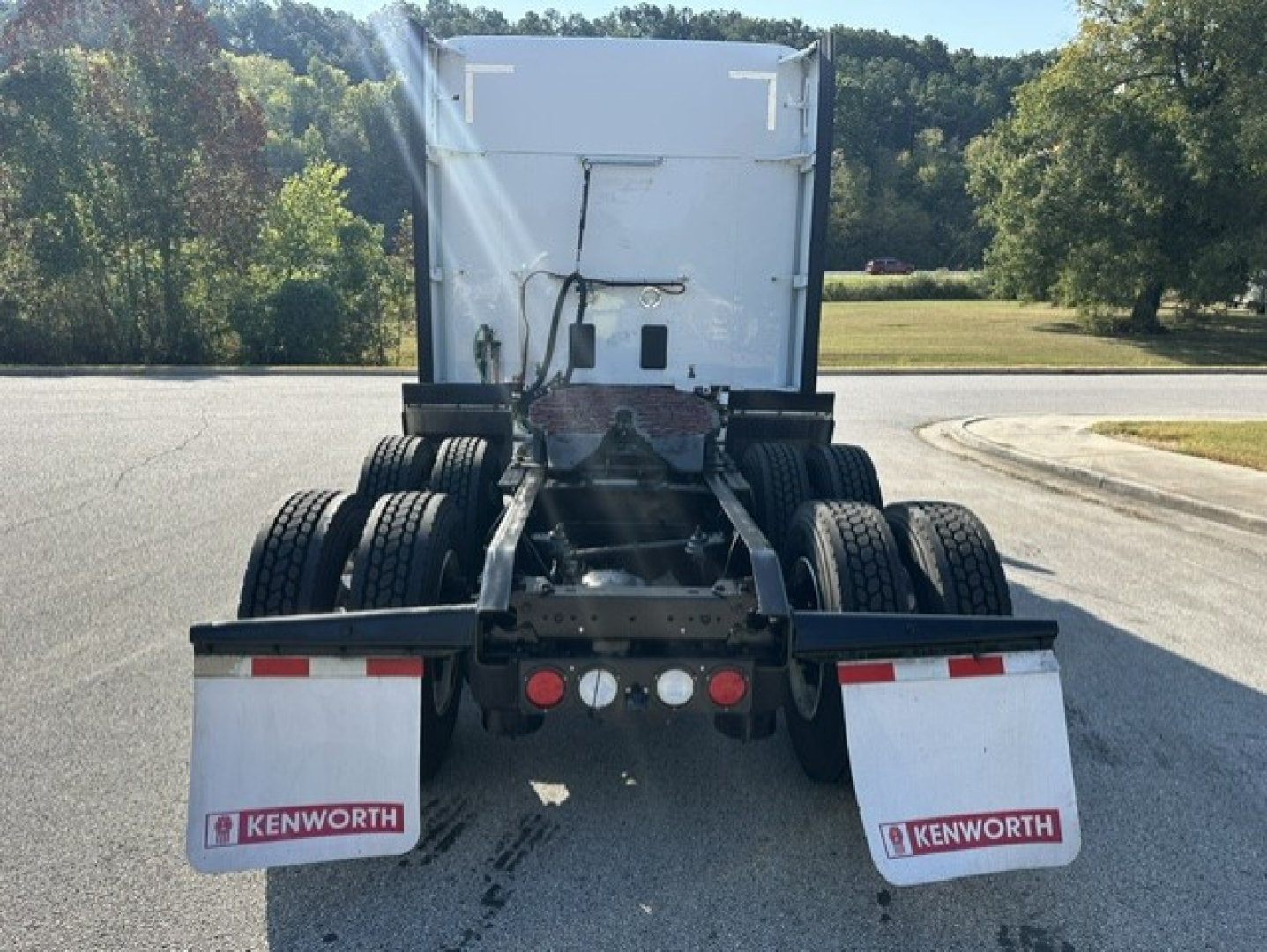 Kenworth T680 tractor rear view showing dual rear axles, mud flaps with Kenworth logo, and rear bumper with lights.