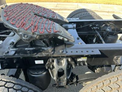 Kenworth T680 chassis view showing fifth-wheel and frame components with visible fuel/air lines and suspension, partial rear wheels.