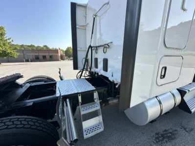 Kenworth T680 truck view showing side steps and cab access area with metal step plate and fuel tank area.
