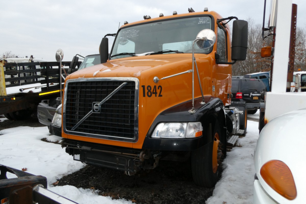 Volvo VNM42T conventional daycab truck front view showing orange cab with number 1842 and large grille