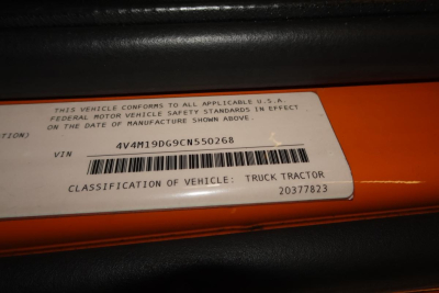 VIN plate on orange truck showing VIN 4V4M19DG9CN550268 with barcode and classification 'TRUCK TRACTOR' label.