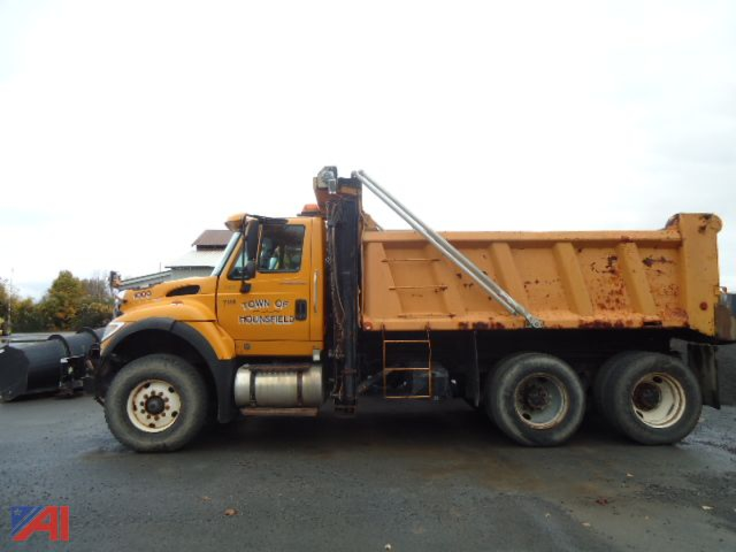 Dump truck side view showing 2005 International WorkStar 7600 with orange cab and dump bed, dual rear axles, Town of Tonawanda branding on door.