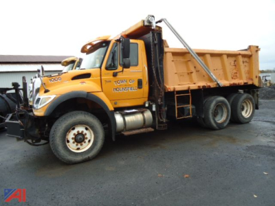 Dump truck with orange cab and dump bed showing side text 'TOWN OF HOUNSFIELD' and International logo.