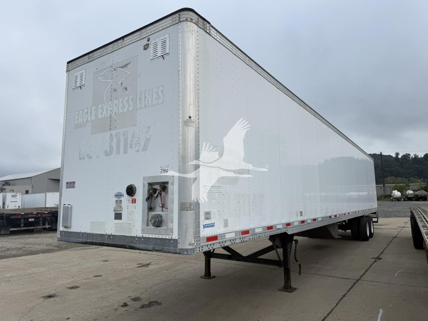 Trailer side and rear view showing Eagle Express Lines logo on silver exterior; rear doors with latches; elevated landing legs; VIN plate area not clearly readable; no door or wheel details visible.
