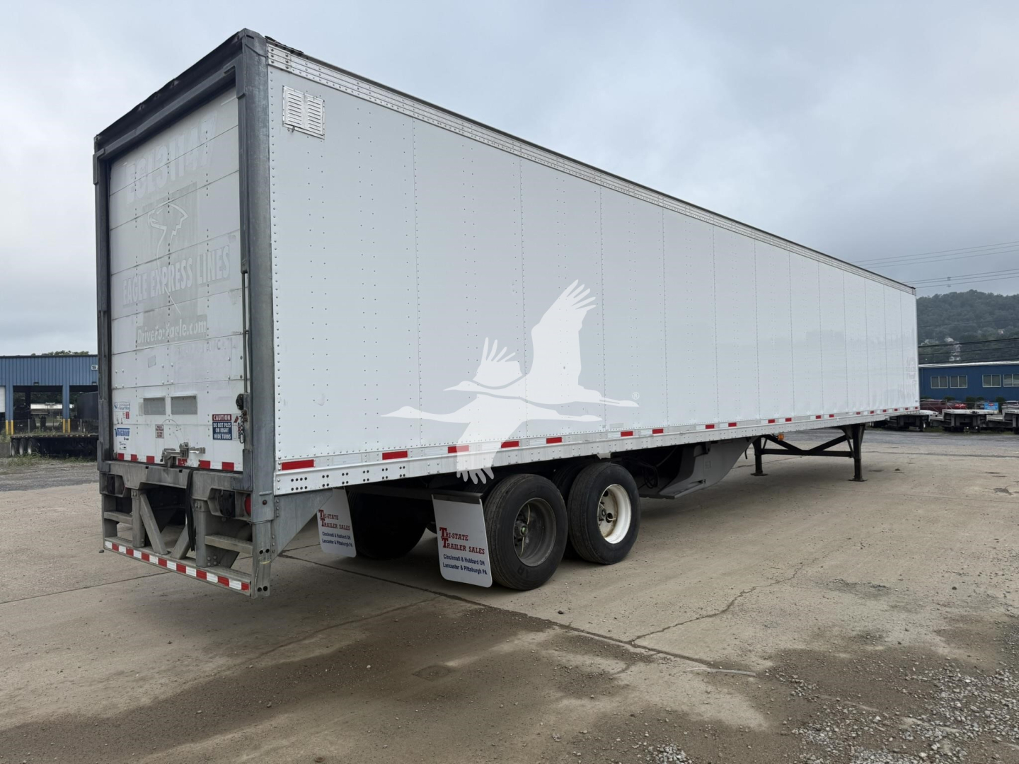 Trailer rear and side view of a white Vanguard Vip 4000 trailer with tandem axles, parked in a lot.