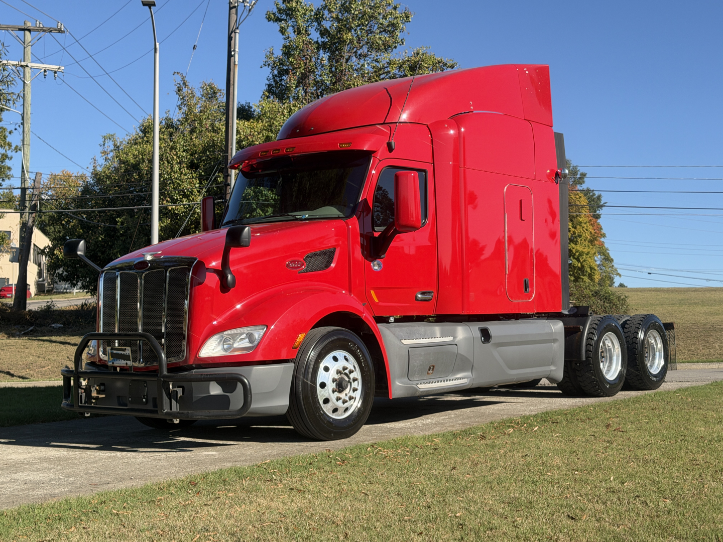 Peterbilt 579 conventional sleeper truck in red, side view showing dual rear axles, chrome bumper guard, and tall sleeper cab.