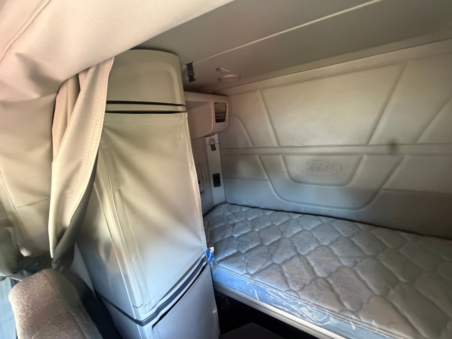 Peterbilt 579 sleeper cab interior showing bunk bed with mattress and storage cabinet.