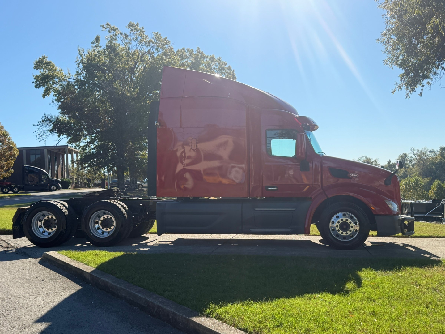 Peterbilt 579 truck in profile view with sleeper cab, maroon exterior, showing side of tractor and fuel tanks.