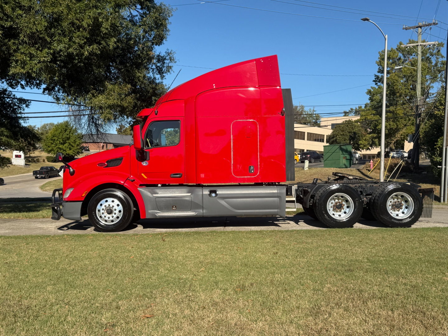 Peterbilt 579 tractor unit in red, side view showing sleeper cab, dual rear axles, and chrome fuel tanks.
