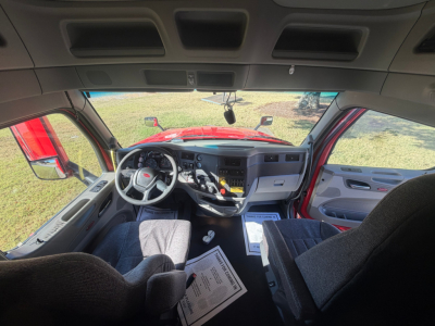 Peterbilt 579 cabin interior showing steering wheel, dashboard, and driver seat with paperwork on floor.