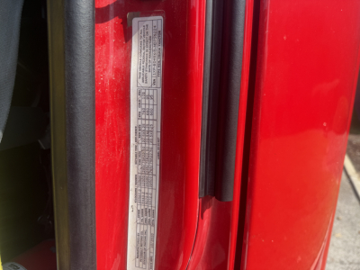 Vehicle door jamb label with compliance and spec text on a red Peterbilt truck. Includes small printed table data