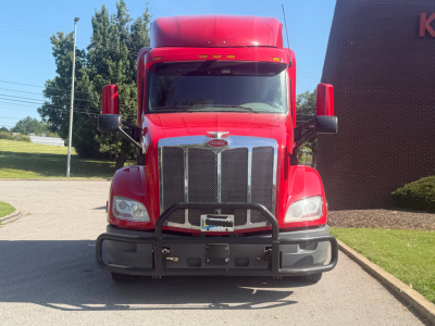 Peterbilt 579 truck from the front view with large grille, headlights, and bumper; red cab and hood; no visible text on the truck aside from badge at center grille.