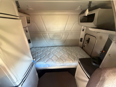 Peterbilt 579 sleeper cab interior showing bed with quilted mattress and side storage compartments.