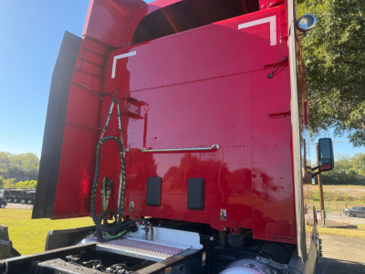 Peterbilt 579 truck cab rear view showing red cargo area, side step, and hydraulic lines near the sleeper window.
