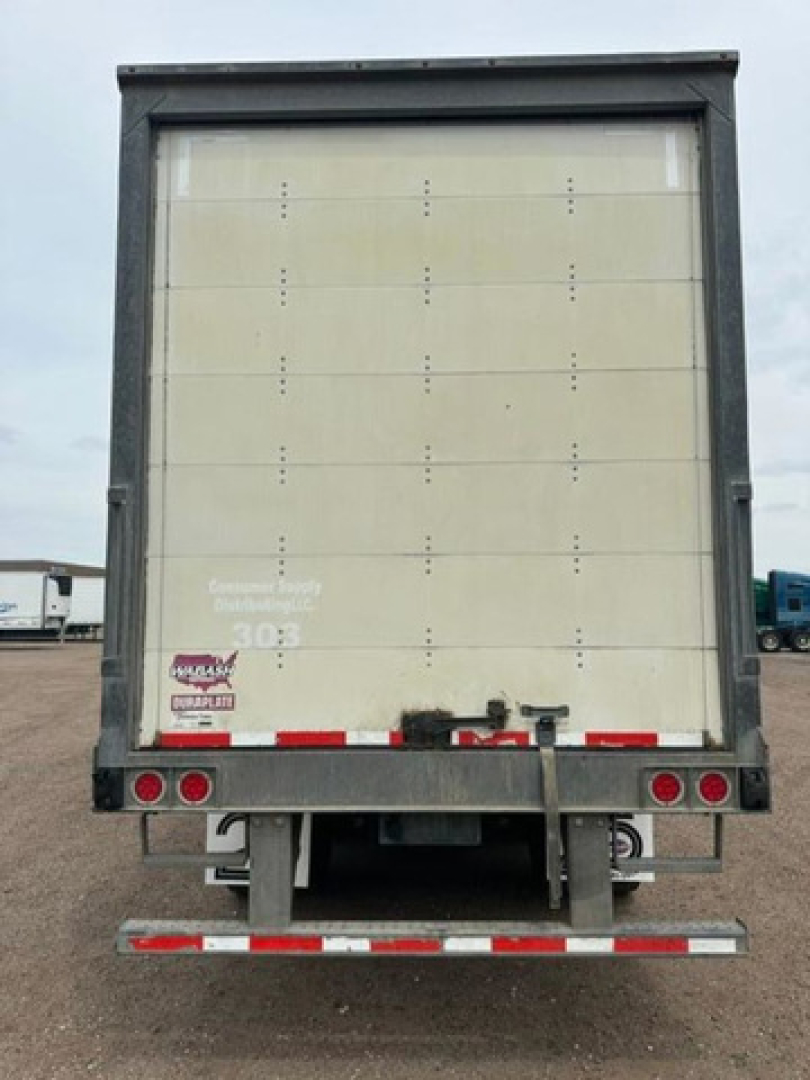 Rear view of a 2016 Wabash van trailer with closed white rear doors, black frame, red and white reflective tape, and bumper with dual taillights.