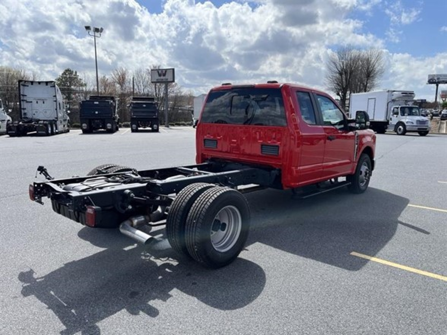 Truck cab and chassis with red cab, rear chassis exposed, left side view showing frame and tires.