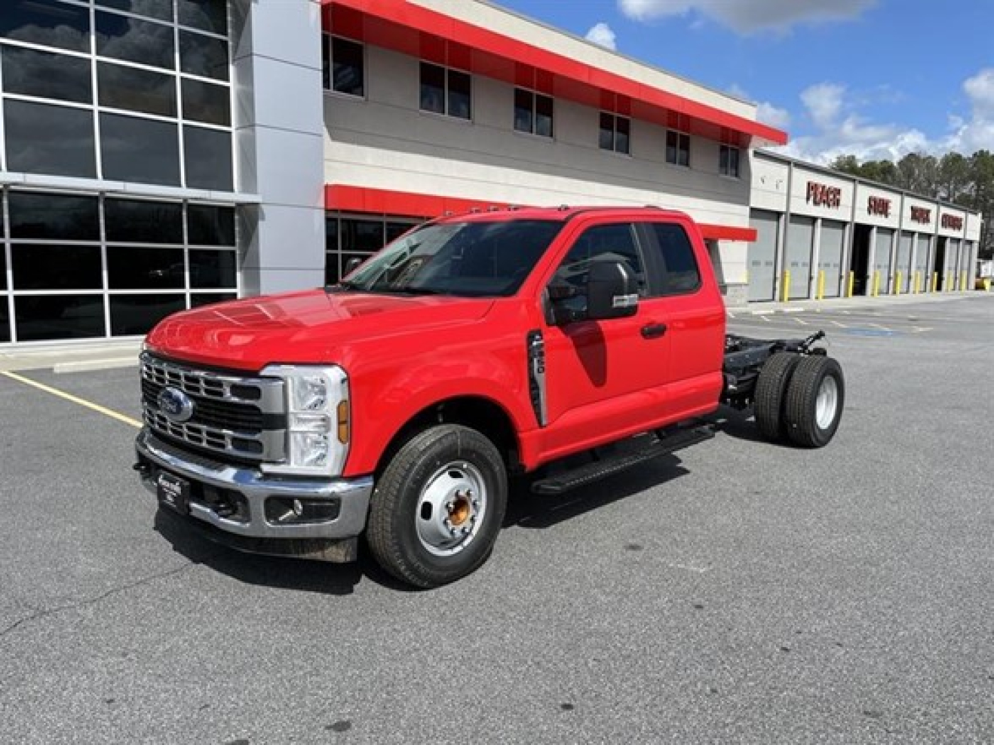 Red 2026 Ford F-350 SD cab chassis with extended cab, shown in dealership lot.