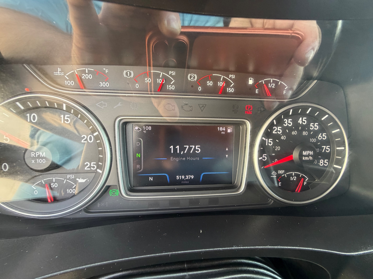 Dashboard of a truck showing instrument cluster with speedometer, tachometer, and central digital display reading 11,775 engine hours. Various gauges and warning indicators visible.