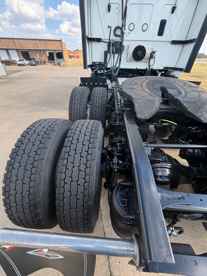 Truck chassis rear with dual rear axles and fifth-wheel area showing tires and suspension components.