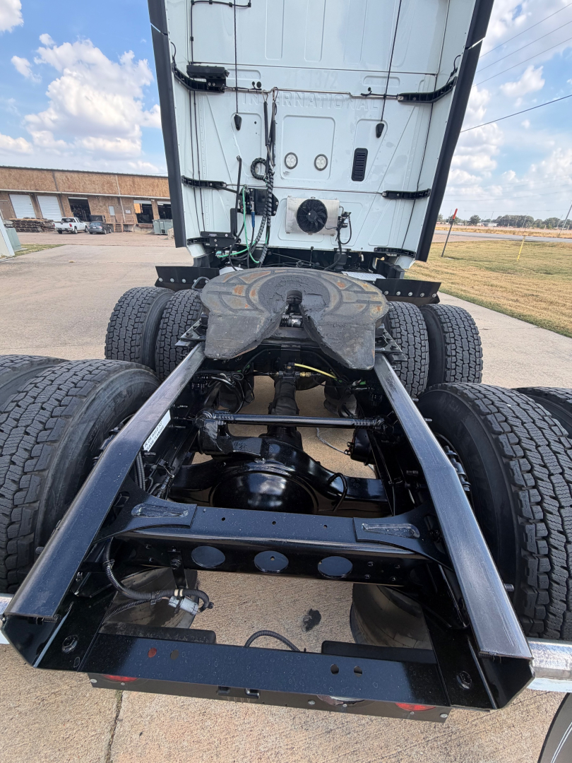 Truck chassis and rear cab view showing fifth wheel, dual rear axles, and frame rails for a 2021 International LT625 with visible components and drivetrain.