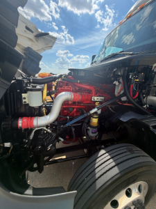 International LT625 engine bay with red engine block, white intake hose, and various hoses and components visible.