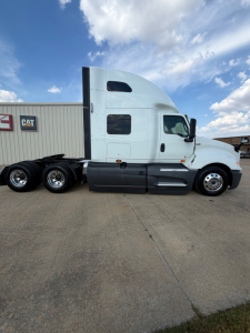 Truck side profile showing sleeper cab of a white 2021 International LT625 with rear axles and fuel tanks.