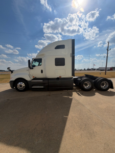 International LT625 truck cab and chassis side profile showing sleeper cab and triple rear axles in a parking lot.