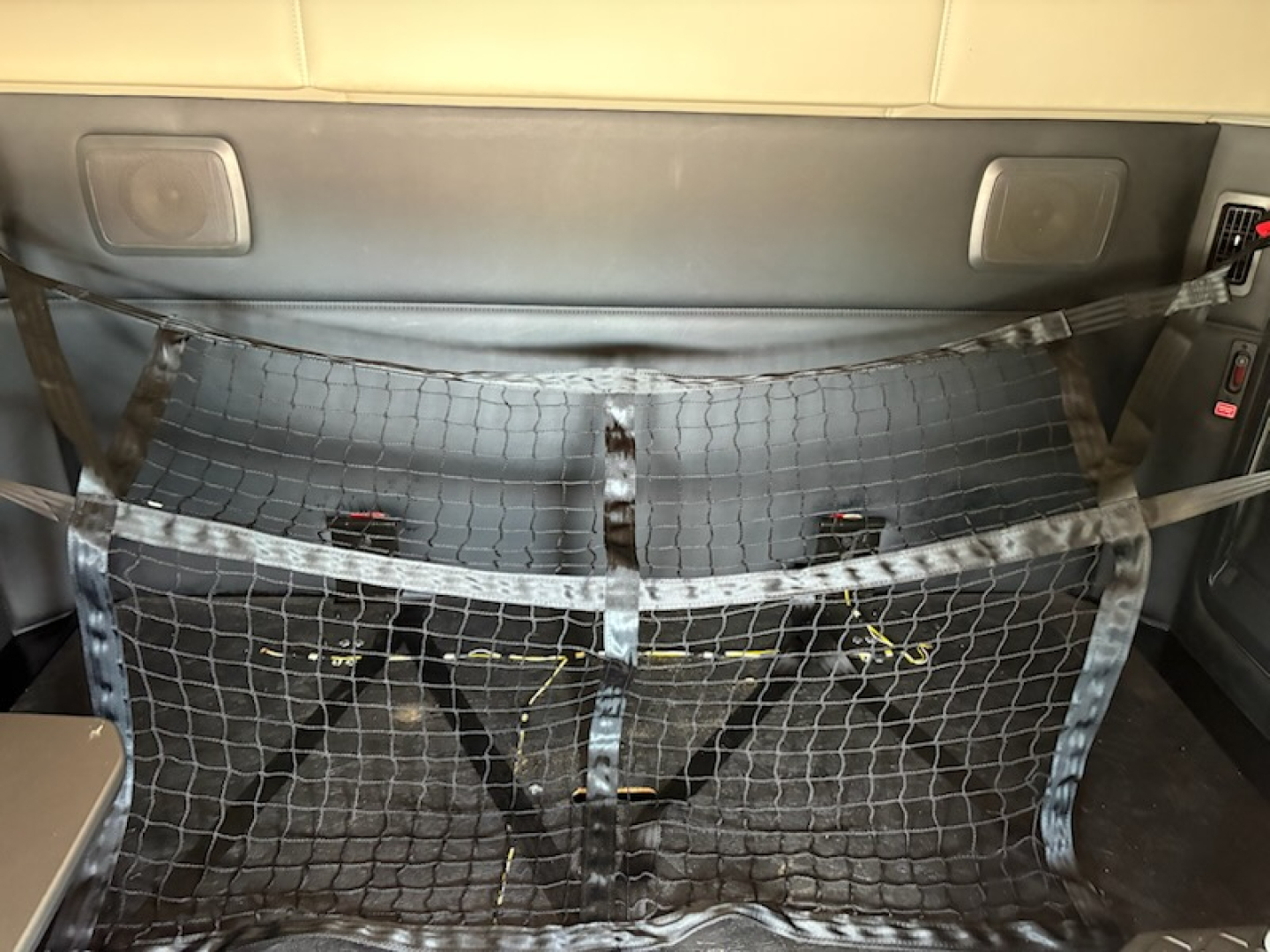 Kenworth truck interior cargo area with a protective netting barrier and visible wiring beneath.