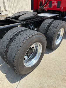 Kenworth T680 rear axle assembly showing dual rear tires and chrome rims with visible fifth wheel mounting area and chassis frame.