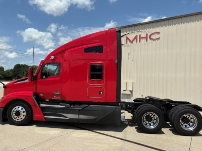 Kenworth T680 tractor cab side view with bright red paint, sleeper, dual rear axles, chassis, and black steps.