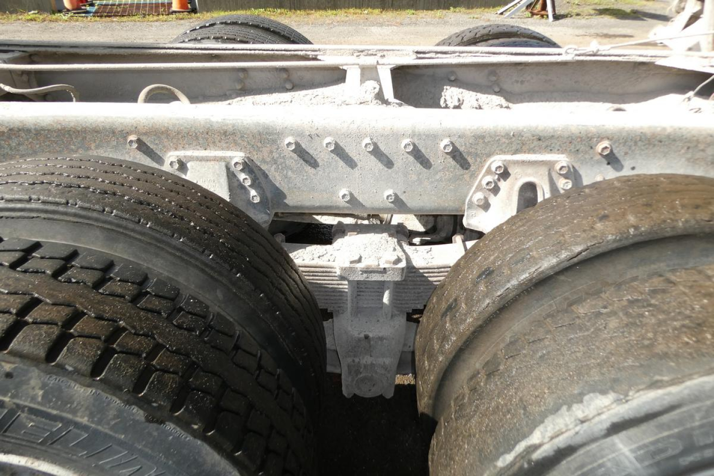 Peterbilt truck chassis with dual rear axles and suspension components; visible tires and frame, metal brackets and bolts.