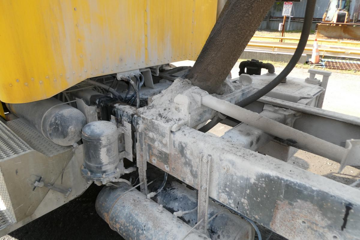 Peterbilt truck frame and hydraulic components showing chassis, hoses, and metal brackets with a yellow body panel in the background.