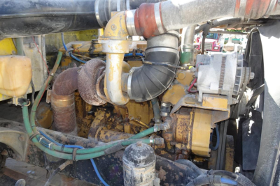 Peterbilt 357 engine bay view showing yellow diesel engine with exhaust manifold, hoses, and radiator components.