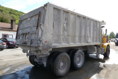 Dump truck cargo bed with Peterbilt 357 rear view showing weathered metal sides and dual rear axles.