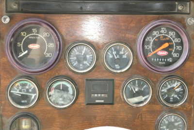 Peterbilt dashboard gauges cluster showing RPM, speedometer, volts, oil pressure, fuel, and other indicators in a wood-grain panel.