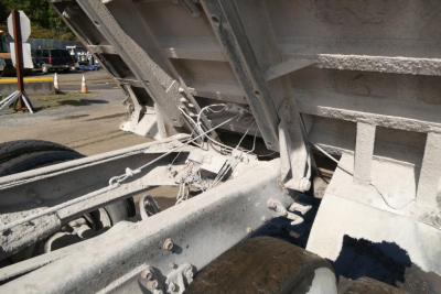 Truck chassis and dump bed frame with steel supports and chains; no legible text visible on components.