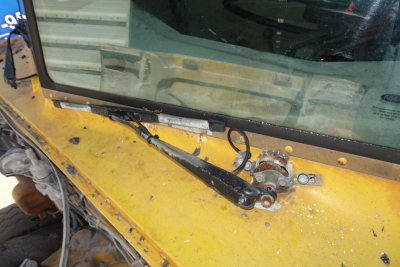 Peterbilt truck cab top view showing windshield wipers and mounting assembly on yellow paint; some wear and dirt.
